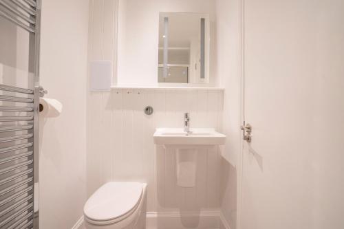a white bathroom with a toilet and a sink at The Woodside in Doune