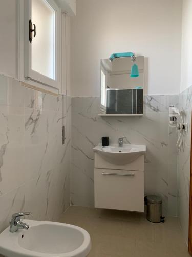 bagno bianco con lavandino e specchio di Il Canaletto Apartments a Porto Cesareo