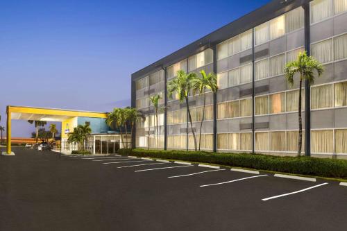 um parque de estacionamento em frente a um edifício com palmeiras em Days Inn by Wyndham Miami International Airport em Miami