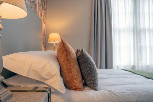 a bedroom with a bed with pillows and a window at The Woodside in Doune