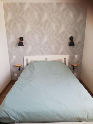 - un lit blanc dans une chambre avec deux lumières sur le mur dans l'établissement Jolie petite maison indépendante de plain-pied, à Pont-de-Buis