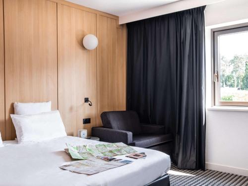 um quarto de hotel com uma cama e uma cadeira em Mercure Tours Sud em Joué-lés-Tours