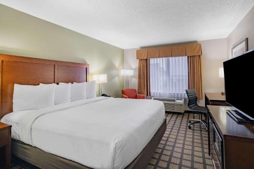 a hotel room with a large bed and a television at Baymont by Wyndham Gurnee in Gurnee