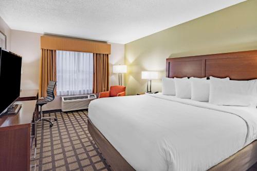 um quarto de hotel com uma cama grande e uma televisão de ecrã plano em Baymont by Wyndham Gurnee em Gurnee