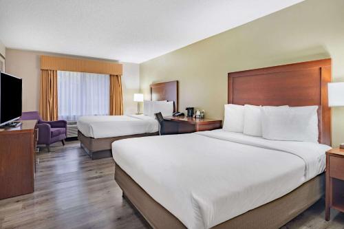a hotel room with two beds and a television at Baymont by Wyndham Gurnee in Gurnee