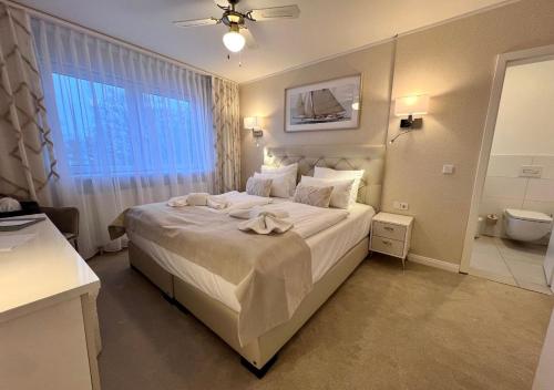 a bedroom with a large white bed and a bathroom at Hotel Resort Märkisches Meer in Diensdorf-Radlow