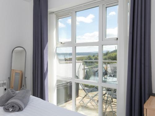 a bedroom with a bed and a large window at Pass the Keys 2 Bed Sea View Apartment with Balcony Parking in Benllech