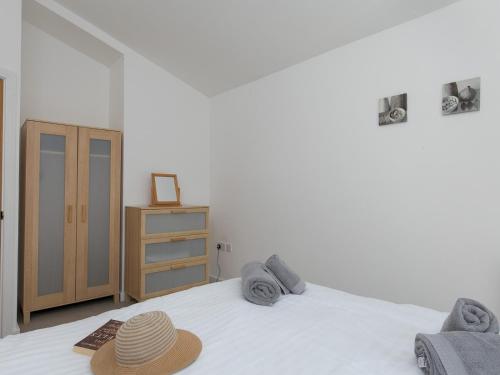 a bedroom with a bed with a hat on it at Pass the Keys 2 Bed Sea View Apartment with Balcony Parking in Benllech