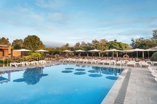 einen Pool mit Stühlen und Sonnenschirmen in einem Resort in der Unterkunft Hotel Mediterraneo in Roses