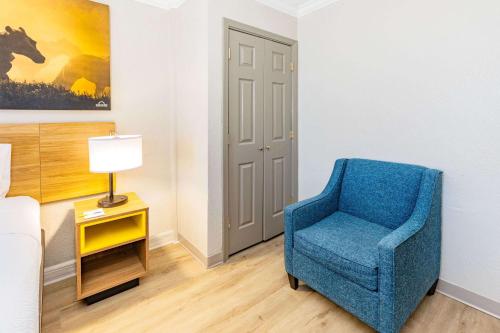 a blue chair in a room with a lamp at Days Inn by Wyndham Del Rio in Del Rio