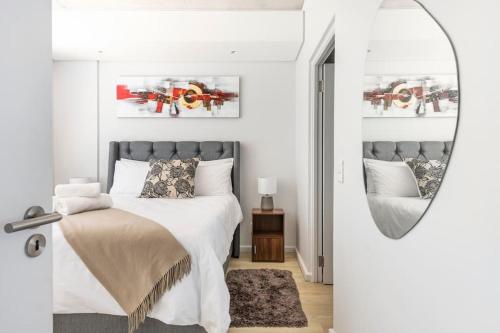 a bedroom with a bed and a mirror at Condo at Woodstock Quarters - Stylish 2 ensuite Bedroom Apartment with Spacious Balcony in Cape Town