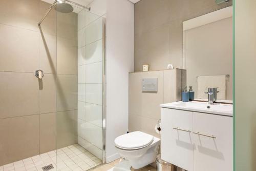 a bathroom with a shower and a toilet and a sink at Condo at Woodstock Quarters - Stylish 2 ensuite Bedroom Apartment with Spacious Balcony in Cape Town