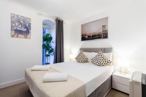 a white bedroom with a large bed and a window at Stay Thames River in London