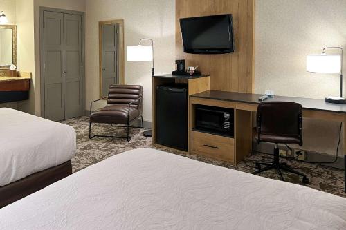 Habitación de hotel con cama y escritorio con TV. en Maine Evergreen Hotel, Ascend Hotel Collection en Augusta