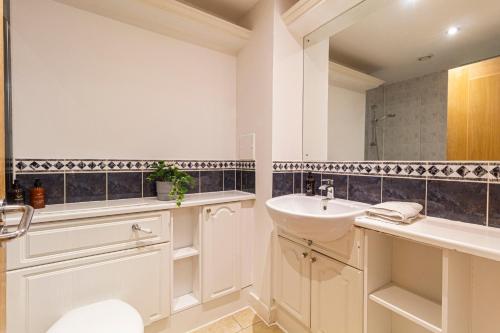 ein Badezimmer mit einem Waschbecken, einem WC und einem Spiegel in der Unterkunft Stay Thames River in London