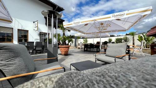 a patio with chairs and a table and umbrellas at Showhotel Seerose in Wolfshain