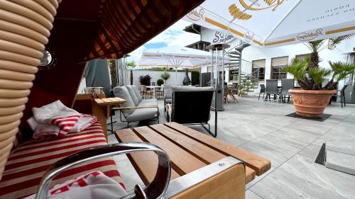 un patio con banco, mesas y sillas en Showhotel Seerose 