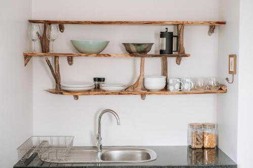 eine Küchentheke mit Holzregalen über einer Spüle in der Unterkunft Pebbles Beach Cottage in Port Elizabeth