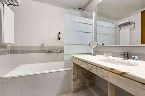 W łazience znajduje się umywalka, wanna i lustro. w obiekcie TRYP by Wyndham Montijo Parque Hotel w mieście Montijo
