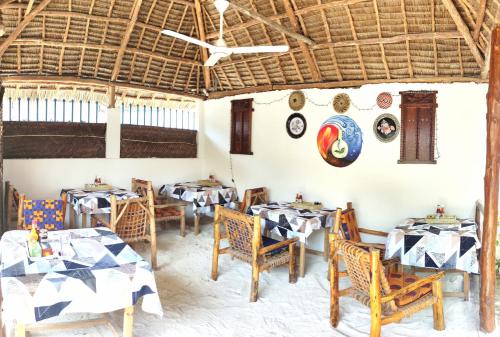a dining room with tables and chairs and a ceiling at MaNa Nungwi in Nungwi