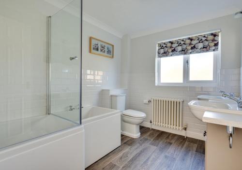 a white bathroom with a tub and a toilet and a sink at Avocet House in Langham