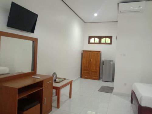 a room with a bed and a desk and a television at Batu Jaran Hill Cottage Uluwatu in Uluwatu