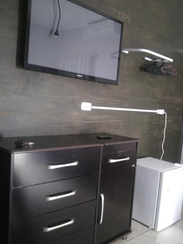 a black dresser with a television on a wall at Lima hospedagem caseira in Olímpia