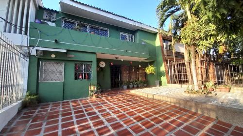 a green building with a brick walkway in front of it at Casa Verde El Golf in Barranquilla