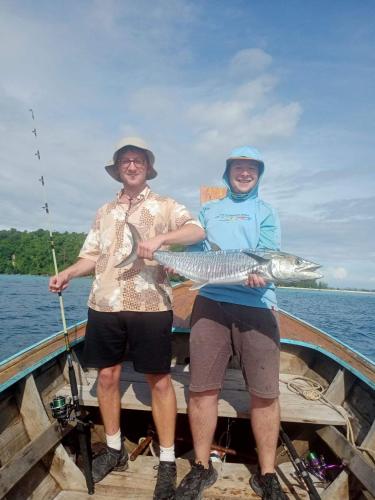 two men standing on a boat holding a fish at P P Garden Home Bungalow in Phi Phi Don