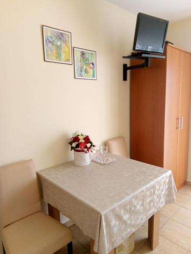 a dining room table with a vase of flowers on it at Apartment Vila MM Srce in Vrdnik
