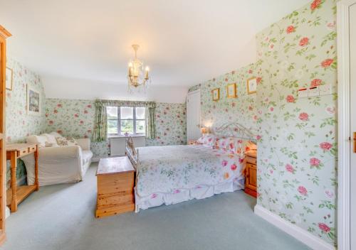 a bedroom with a bed and floral wallpaper at Rainbow Cottage in Long Bredy