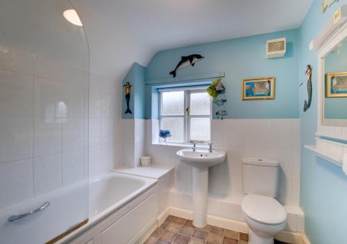 a bathroom with a sink and a toilet and a bath tub at Rainbow Cottage in Long Bredy