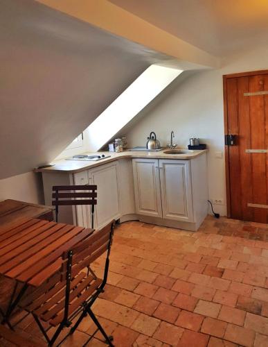 une cuisine mansardée avec un banc en bois et une table dans l'établissement Bel appartement à la Chetardière, à Sainte-Gemme-dʼAndigné