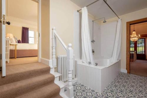 a bathroom with a walk in shower and a staircase at Easter Kincaple Farmhouse, Sleeps 16, St Andrews in St Andrews