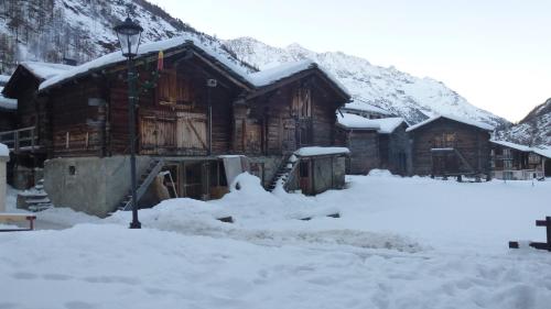 a log cabin with snow on the ground in front at Apartment Theresli First Floor in Saas-Almagell