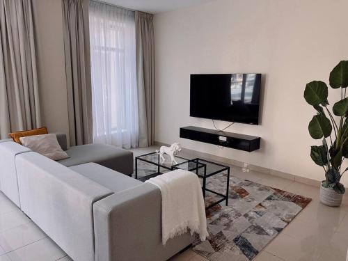 een woonkamer met een bank en een flatscreen-tv bij Huge terrace with canal view & hotels beach access available in Dubai