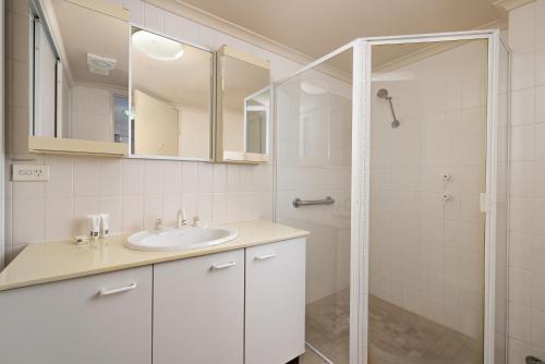 a white bathroom with a sink and a shower at Wahroonga Furnished Apartments in Hornsby