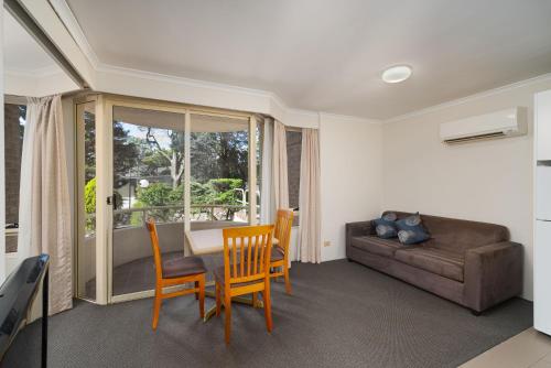 a living room with a couch and a table and chairs at Wahroonga Furnished Apartments in Hornsby
