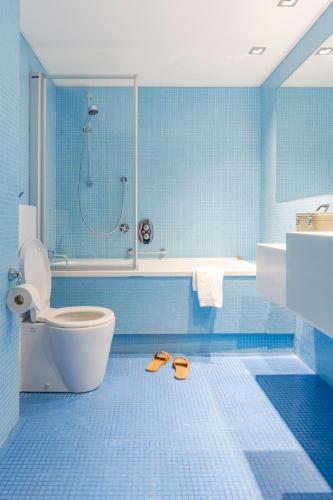 a bathroom with a toilet and a shower and two slippers at Hotel de Milliano in Breskens