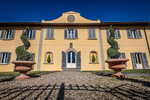 ein Gebäude mit zwei großen Vasen davor in der Unterkunft Luxury Villa Tolomei Gucci near Florence in San Jacopo al Girone