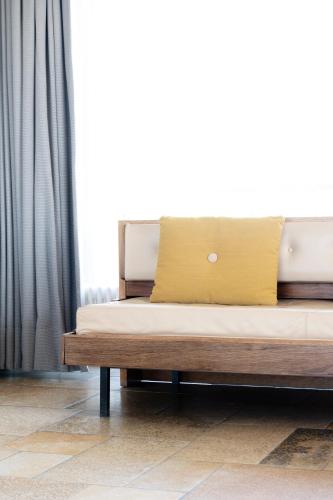 a bed with a yellow pillow on top of it at Hotel de Milliano in Breskens