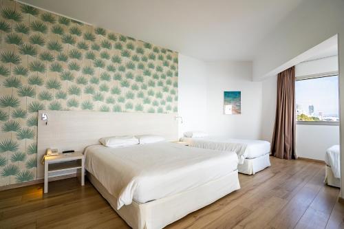 two beds in a hotel room with green wallpaper at Harmony Bay Hotel in Limassol