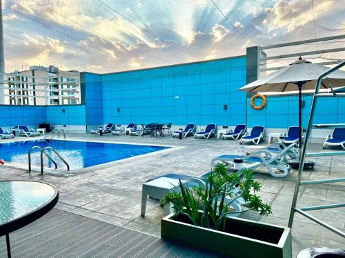 a pool on top of a building with chairs and an umbrella at Copthorne Hotel Sharjah in Sharjah