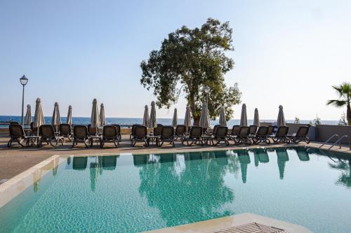 a swimming pool with chairs and umbrellas at Harmony Bay Hotel in Limassol