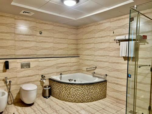 a bathroom with a tub and a toilet at Copthorne Hotel Sharjah in Sharjah