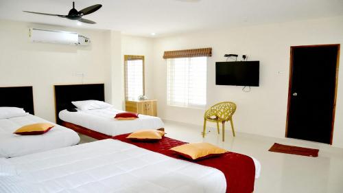 una camera d'albergo con due letti e una TV a schermo piatto di Hotel AK Tirupati a Tirupati
