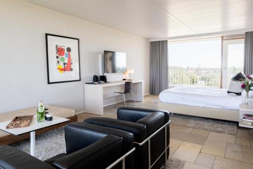 een hotelkamer met een bed, een bank en een tafel bij Hotel de Milliano in Breskens