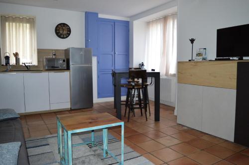 een keuken met blauwe kasten en een tafel in een kamer bij Les volets bleus - duplex proche plage et centre in Arromanches-les-Bains