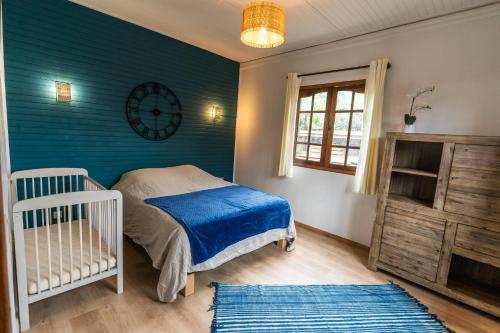 1 dormitorio con cuna y reloj en la pared en Magnifique villa créole VILLA TI BOUT BOIS avec cheminée au tevelave, en Les Avirons