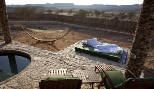a patio with a bed and a hammock and a pool at Arava Land in Zuqim